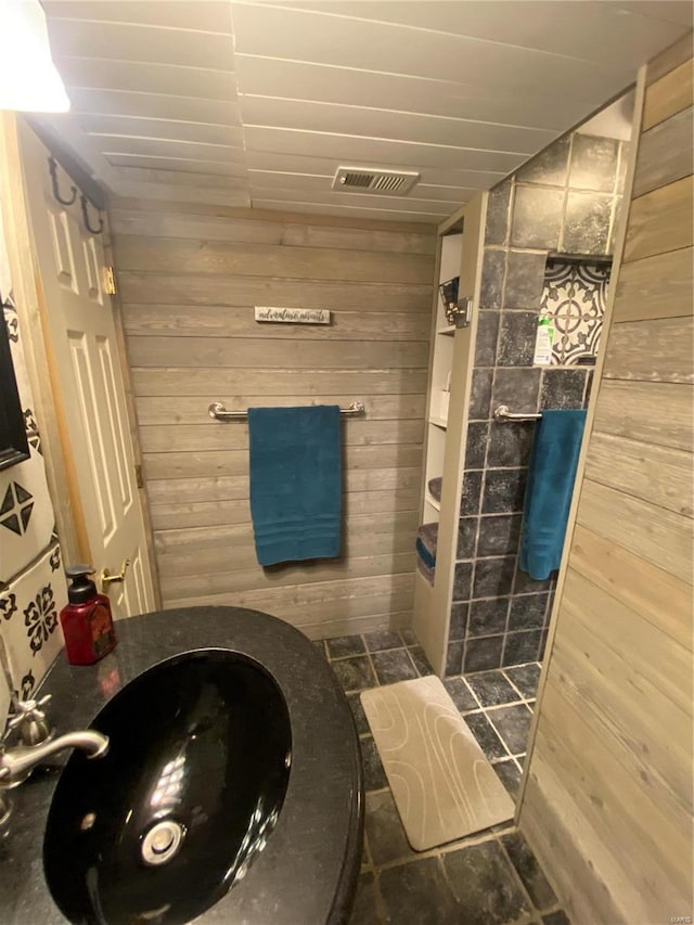 bathroom featuring a shower, sink, and wood walls