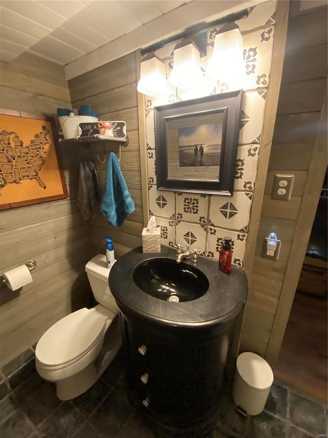 bathroom with wooden walls, vanity, and toilet