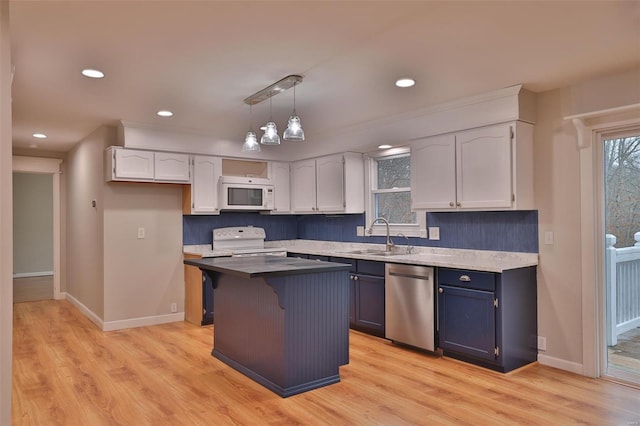 kitchen featuring white cabinetry, a kitchen island, sink, and white appliances