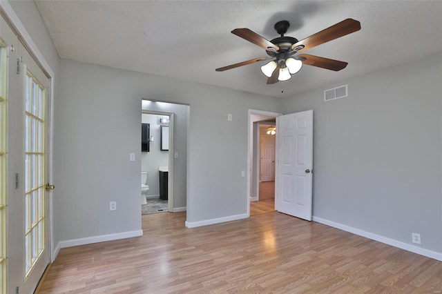 empty room with a textured ceiling and light hardwood / wood-style flooring