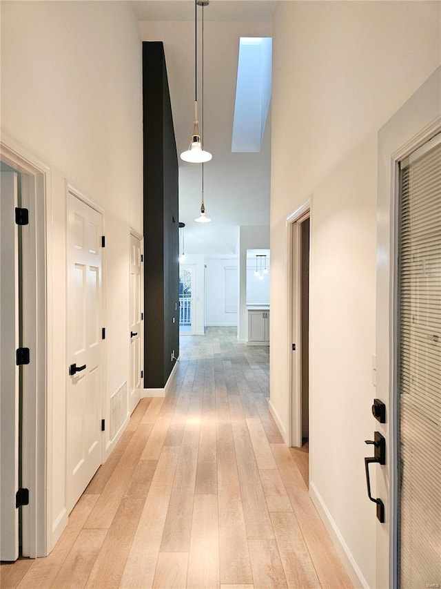 hall with a high ceiling and light wood-type flooring