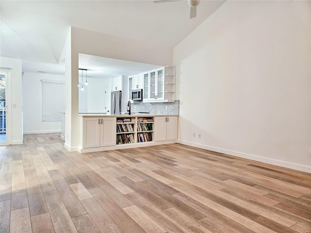 unfurnished living room featuring sink, ceiling fan with notable chandelier, and light hardwood / wood-style floors