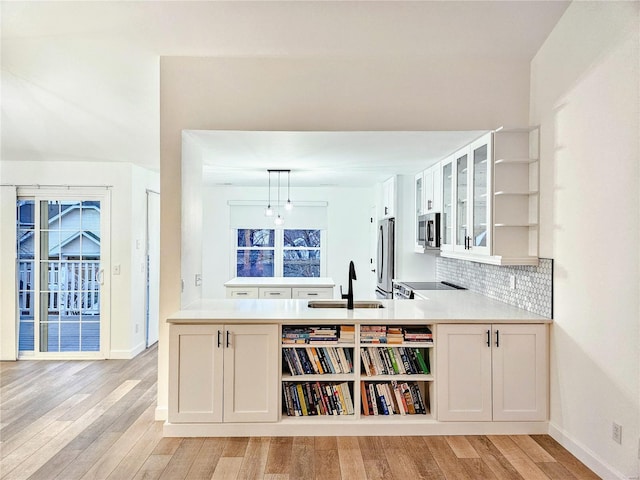 bar with sink, white cabinetry, stainless steel appliances, light hardwood / wood-style floors, and decorative light fixtures