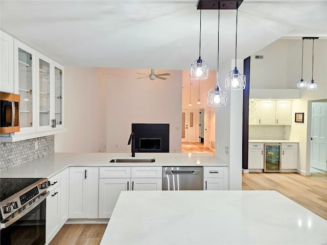 kitchen with wine cooler, sink, pendant lighting, stainless steel appliances, and white cabinets