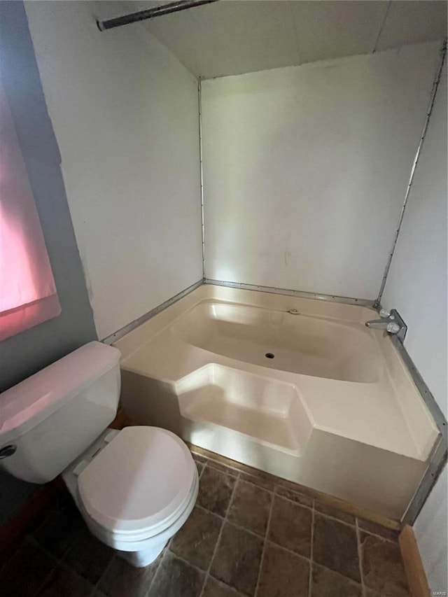 bathroom featuring a tub to relax in and toilet