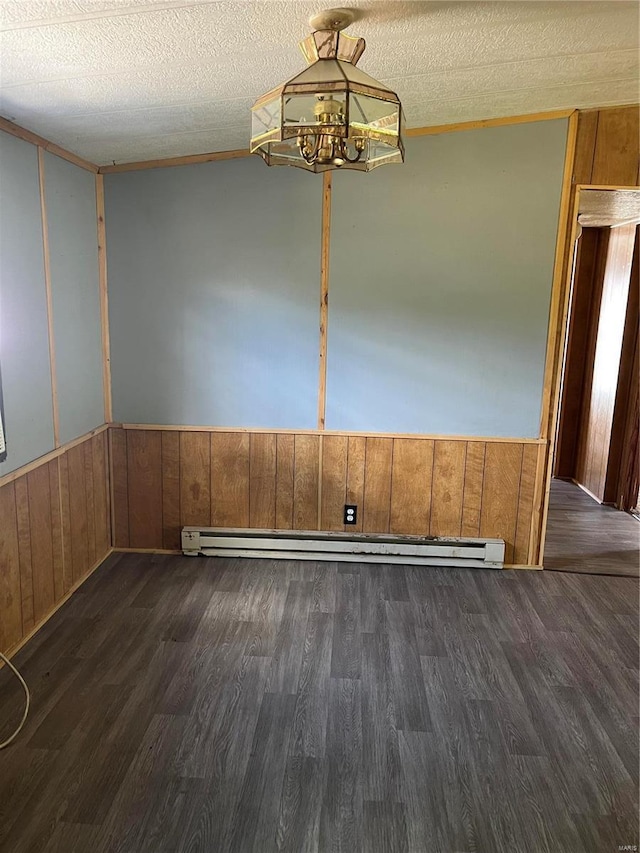 unfurnished dining area featuring a baseboard heating unit, wooden walls, a textured ceiling, and dark hardwood / wood-style floors