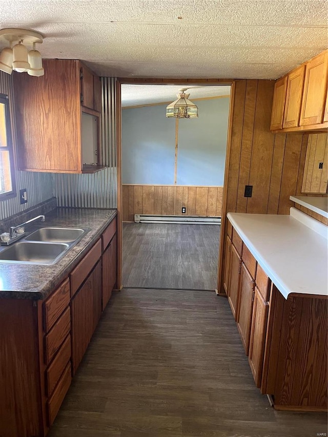 kitchen with sink, dark wood-type flooring, a textured ceiling, and wood walls