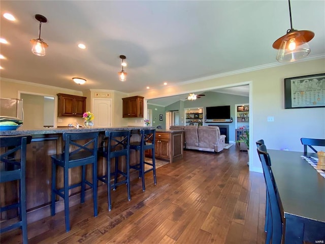 kitchen featuring dark hardwood / wood-style flooring, crown molding, fridge, and a breakfast bar