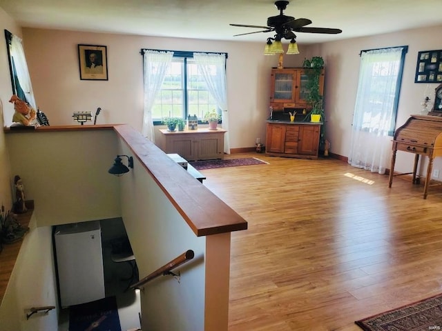 stairway with hardwood / wood-style floors, radiator heating unit, and ceiling fan