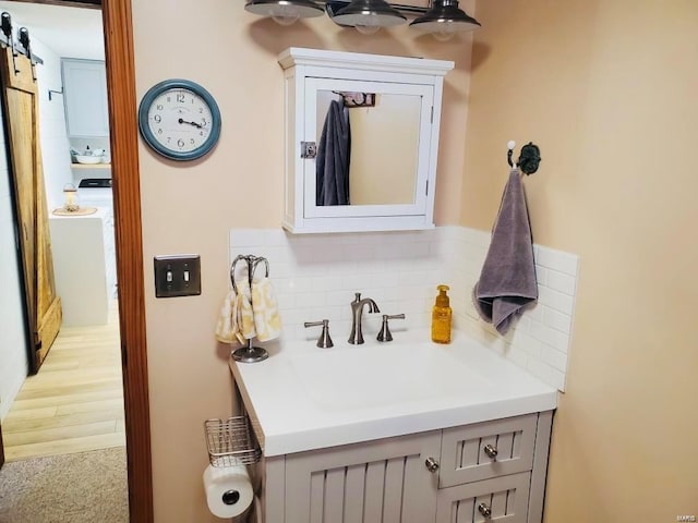 bathroom with tasteful backsplash, vanity, and washer / dryer