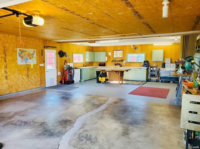 garage featuring a garage door opener, wood walls, and a workshop area