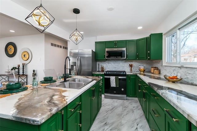 kitchen with sink, hanging light fixtures, green cabinets, stainless steel appliances, and a center island with sink