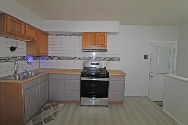 kitchen with gas range, sink, light hardwood / wood-style floors, and decorative backsplash