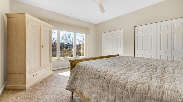 bedroom featuring multiple closets, ceiling fan, and light carpet