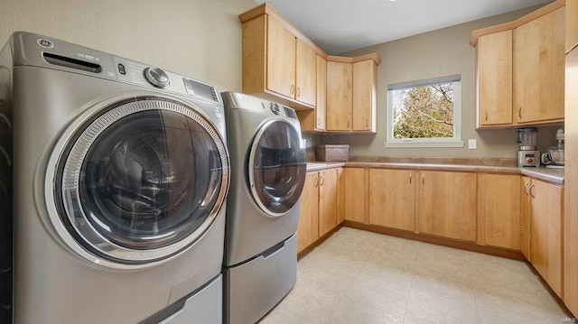 laundry room with separate washer and dryer and cabinets