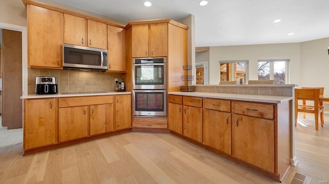 kitchen featuring tasteful backsplash, light wood-type flooring, and appliances with stainless steel finishes