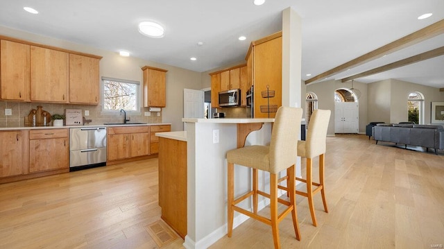 kitchen featuring appliances with stainless steel finishes, sink, light brown cabinetry, and light wood-type flooring