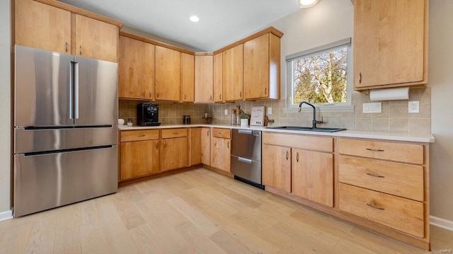 kitchen with light brown cabinetry, sink, tasteful backsplash, light wood-type flooring, and appliances with stainless steel finishes