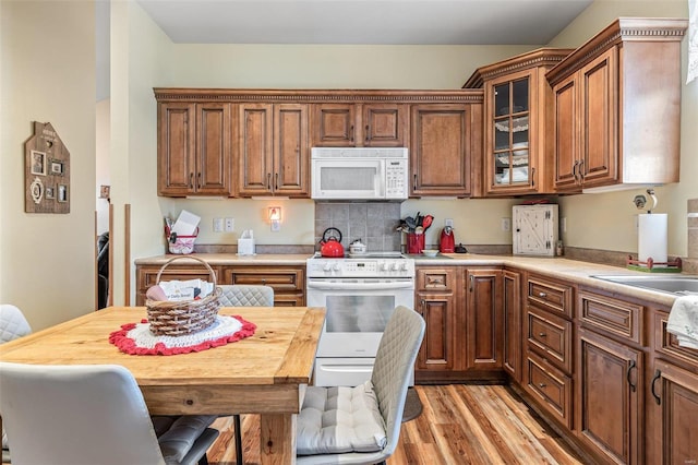 kitchen with white appliances, wood counters, sink, and light wood-type flooring