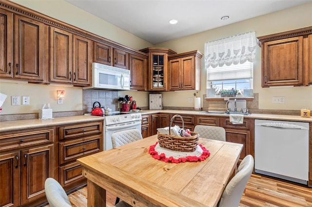 kitchen featuring sink, backsplash, white appliances, and light hardwood / wood-style flooring