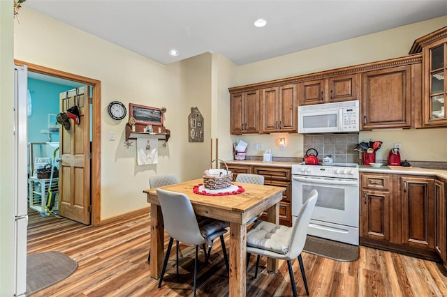 kitchen featuring backsplash, white appliances, and light hardwood / wood-style flooring