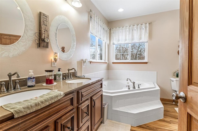 bathroom with tiled tub, vanity, and hardwood / wood-style flooring