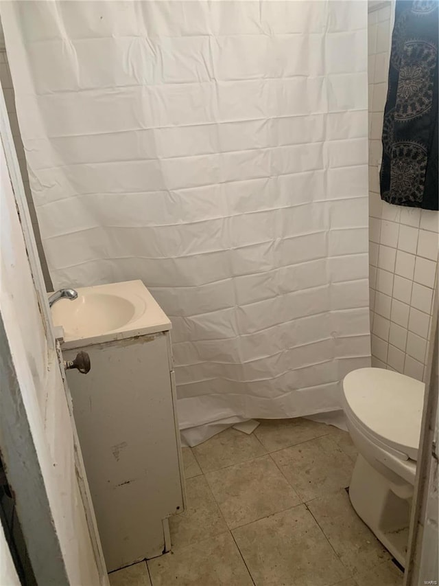 bathroom featuring tile walls, vanity, tile patterned flooring, and toilet