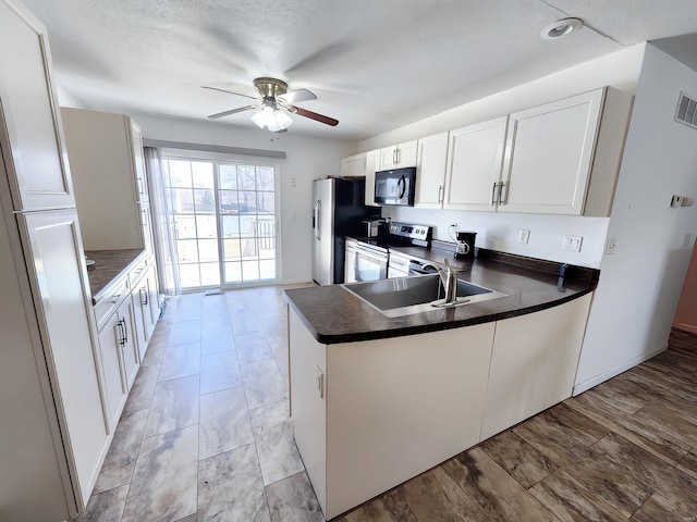 kitchen featuring appliances with stainless steel finishes, white cabinetry, sink, ceiling fan, and kitchen peninsula