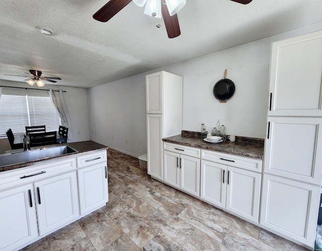 kitchen with white cabinetry, sink, ceiling fan, and a textured ceiling