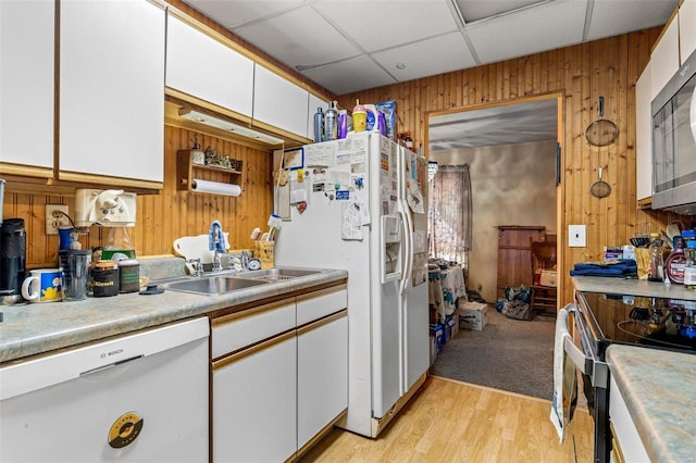 kitchen featuring sink, wooden walls, stainless steel appliances, and white cabinets