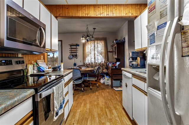 kitchen featuring hanging light fixtures, light hardwood / wood-style floors, white cabinets, and appliances with stainless steel finishes