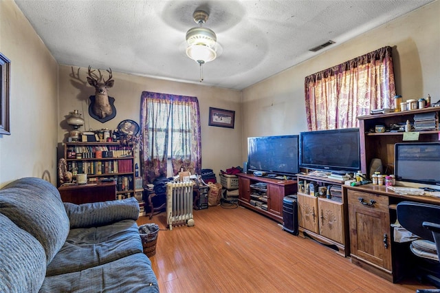 home office with ceiling fan, a textured ceiling, and light wood-type flooring