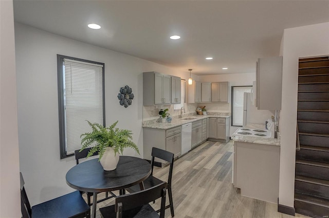kitchen featuring gray cabinets, sink, hanging light fixtures, light hardwood / wood-style floors, and white appliances