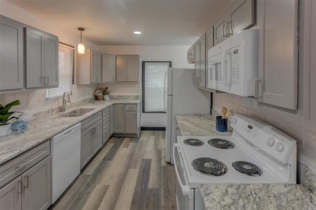 kitchen featuring sink, white appliances, hardwood / wood-style flooring, gray cabinetry, and decorative light fixtures