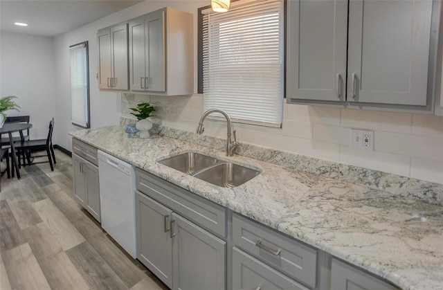 kitchen with sink, dishwasher, gray cabinetry, backsplash, and light hardwood / wood-style floors