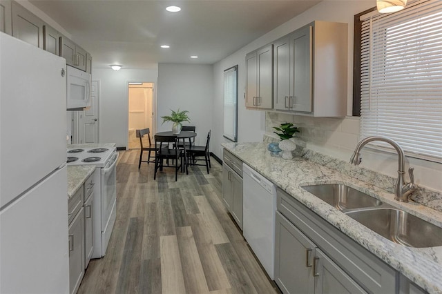 kitchen with wood-type flooring, sink, gray cabinetry, backsplash, and white appliances