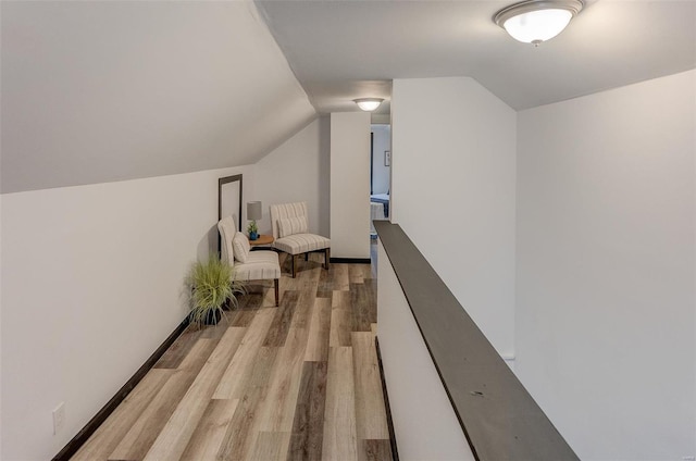 hallway with vaulted ceiling and light hardwood / wood-style floors