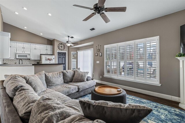 living room featuring lofted ceiling, dark wood-style floors, baseboards, and recessed lighting