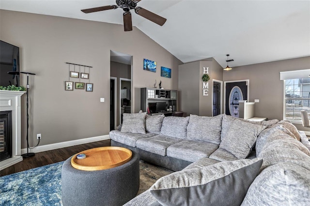 living room featuring lofted ceiling, a ceiling fan, baseboards, dark wood-style floors, and a glass covered fireplace