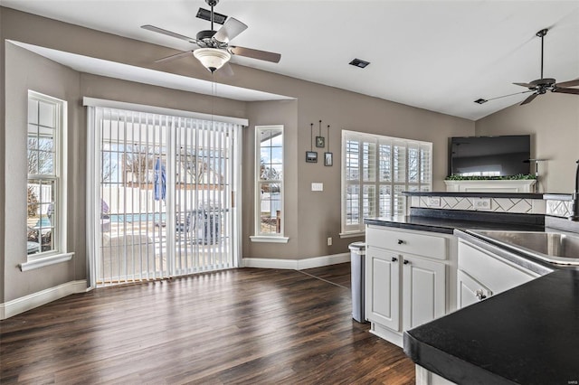 kitchen featuring dark countertops, vaulted ceiling, white cabinetry, and open floor plan