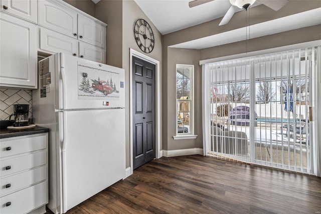 kitchen featuring white cabinets, backsplash, freestanding refrigerator, dark wood-style floors, and dark countertops