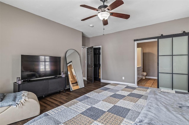 bedroom featuring a barn door, dark wood-type flooring, a ceiling fan, connected bathroom, and baseboards
