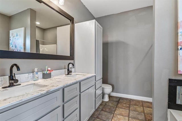 full bathroom featuring a shower, double vanity, a sink, and baseboards