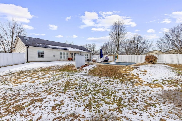 snow covered rear of property featuring fence