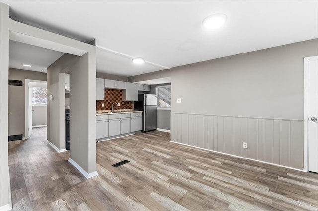 kitchen featuring stainless steel refrigerator, sink, light hardwood / wood-style flooring, and gray cabinetry