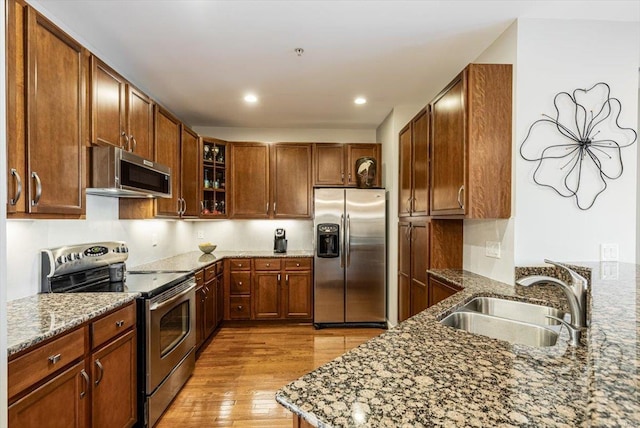 kitchen featuring stone counters, appliances with stainless steel finishes, sink, and light hardwood / wood-style flooring