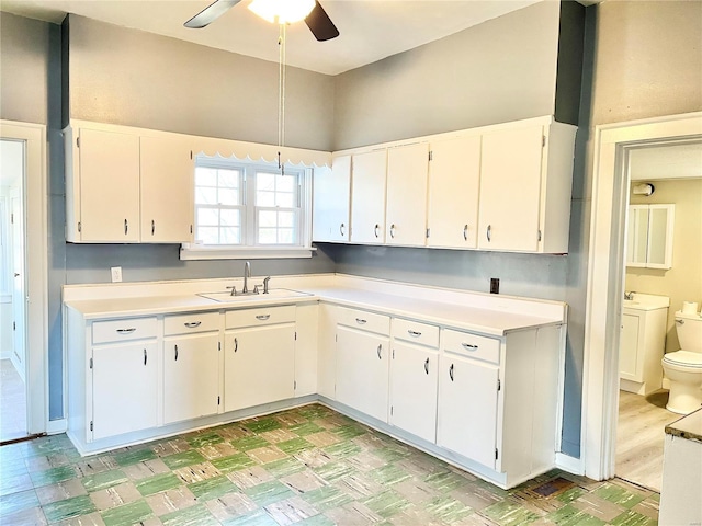 kitchen featuring ceiling fan, sink, and white cabinets