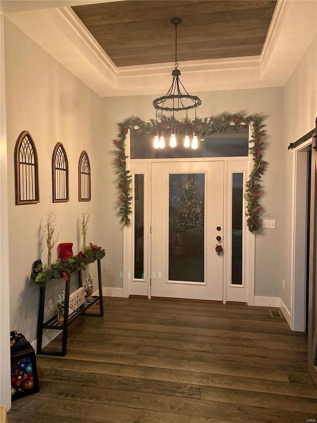 foyer featuring dark hardwood / wood-style floors, wooden ceiling, a raised ceiling, and a barn door