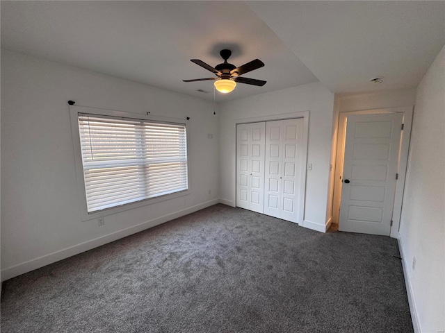 unfurnished bedroom featuring ceiling fan, dark carpet, and a closet