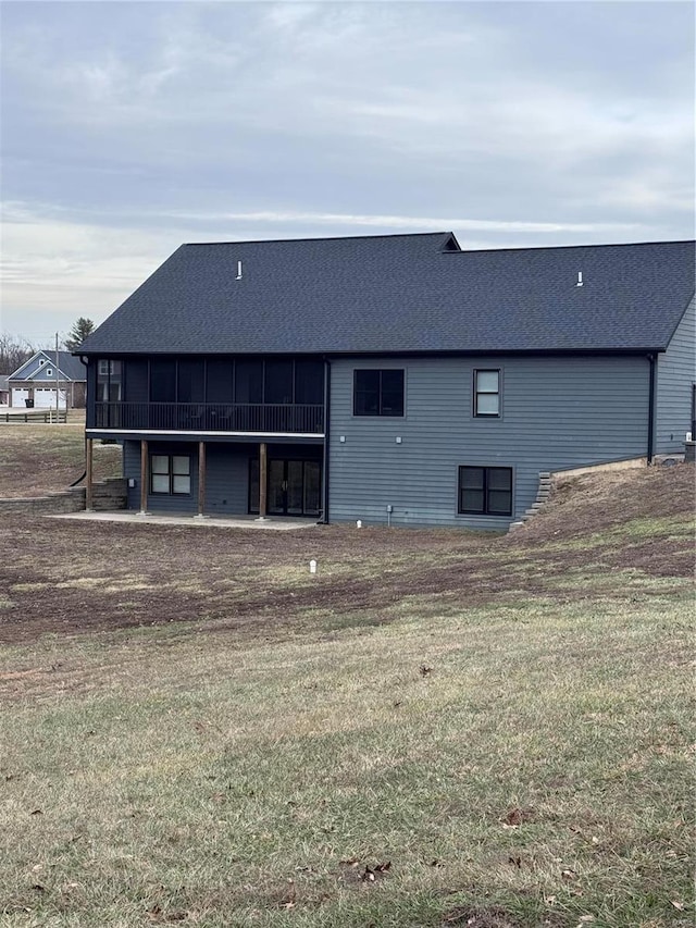 back of house with a sunroom, a patio area, and a lawn